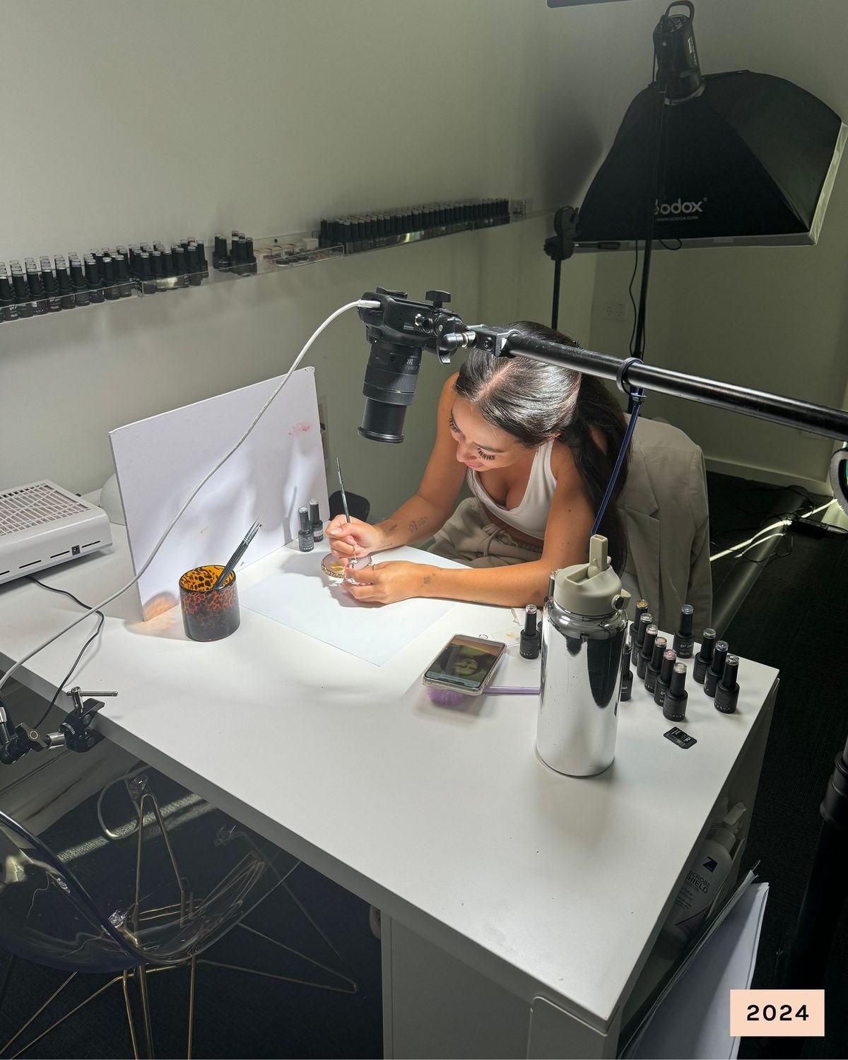 Nail technician calculating nail service prices on a tablet in a modern, organized studio, demonstrating professionalism and business strategy.