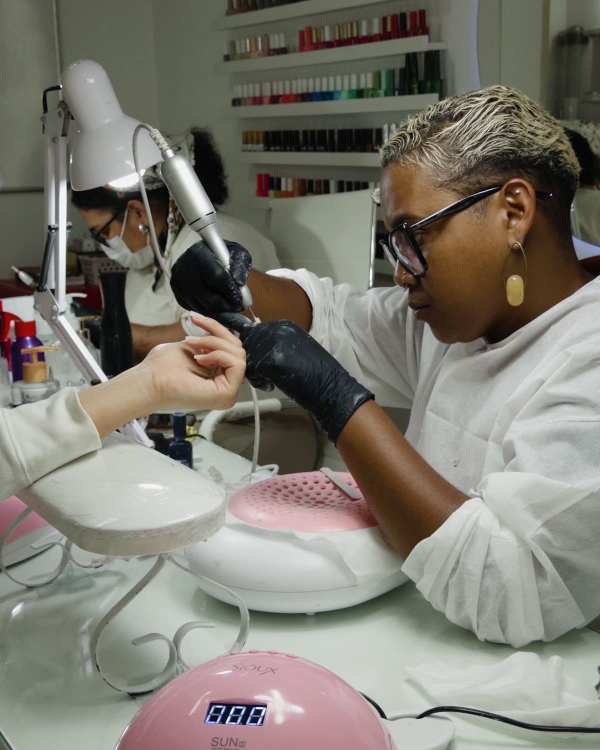Nail technician taking a photo of freshly done nails in a bright, modern studio, demonstrating social media marketing for nail techs.