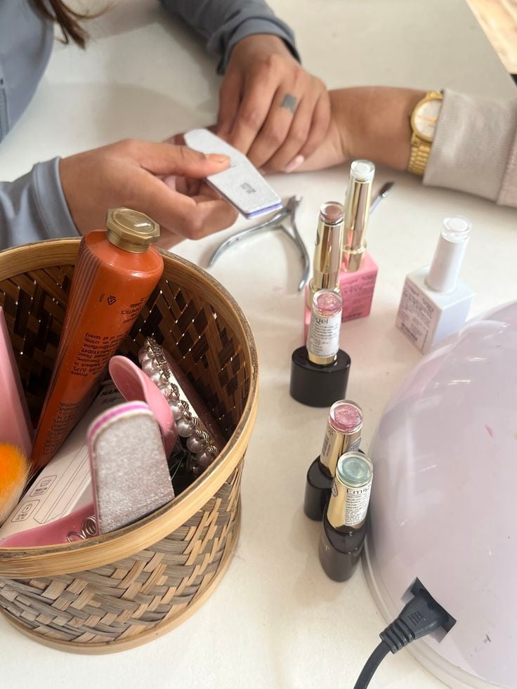 Nail technician carefully filing a client’s nails in a bright, professional studio, demonstrating safe nail care practices to prevent damage.