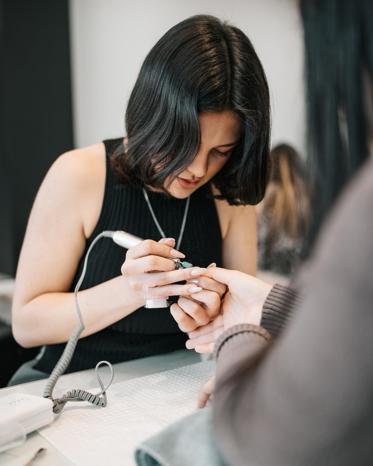 Nail technician welcoming a client in a modern nail studio, demonstrating client attraction and business growth strategies.