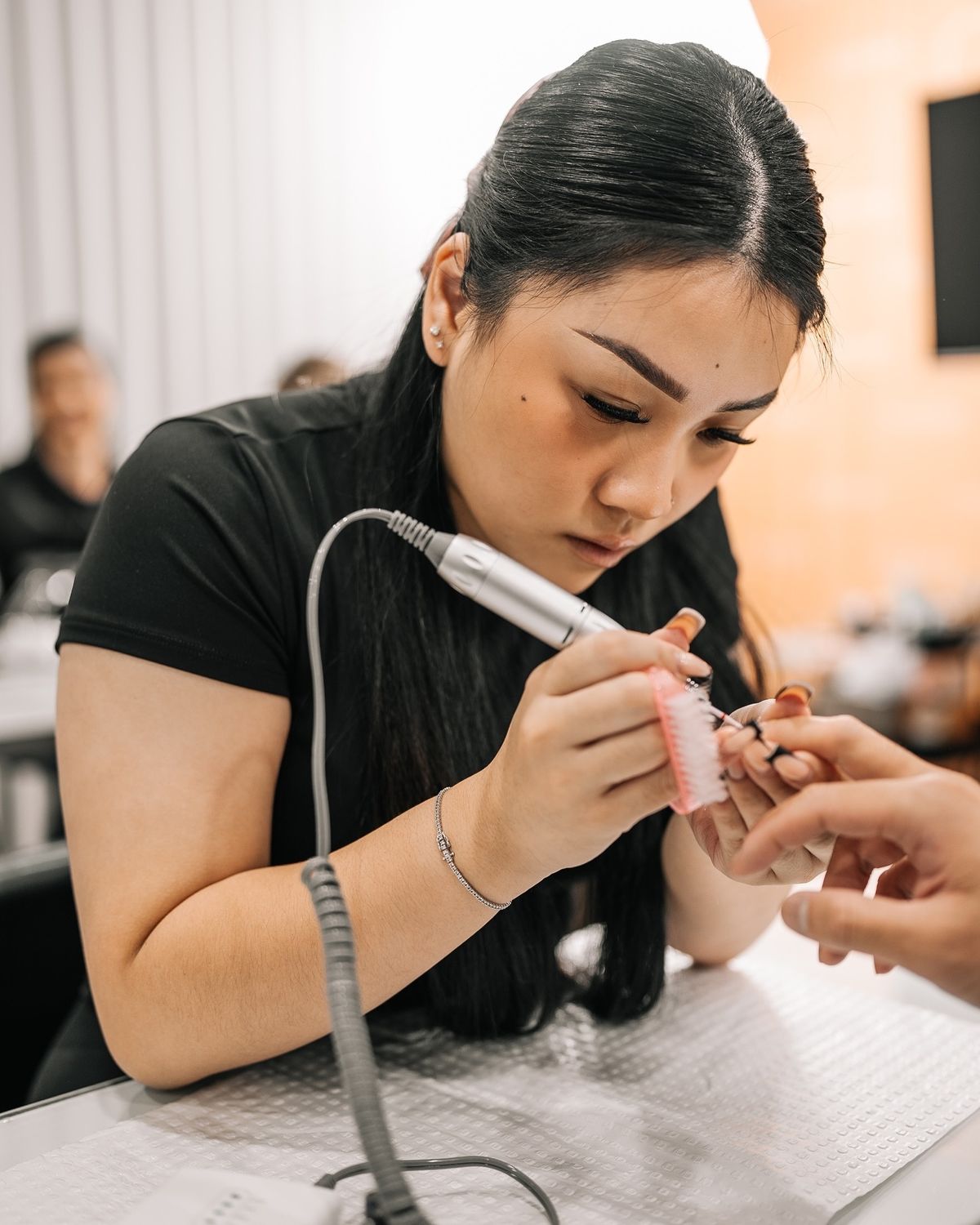 Nail technician calculating service pricing in a modern studio, demonstrating how to set profitable nail service prices.
