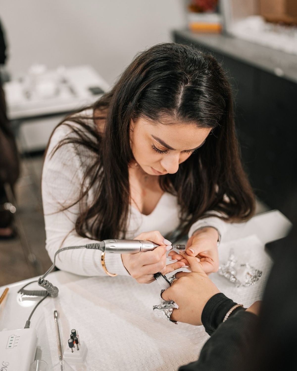 Nail technician calmly discussing a client concern in a clean, modern studio, demonstrating professional complaint management for nail techs.