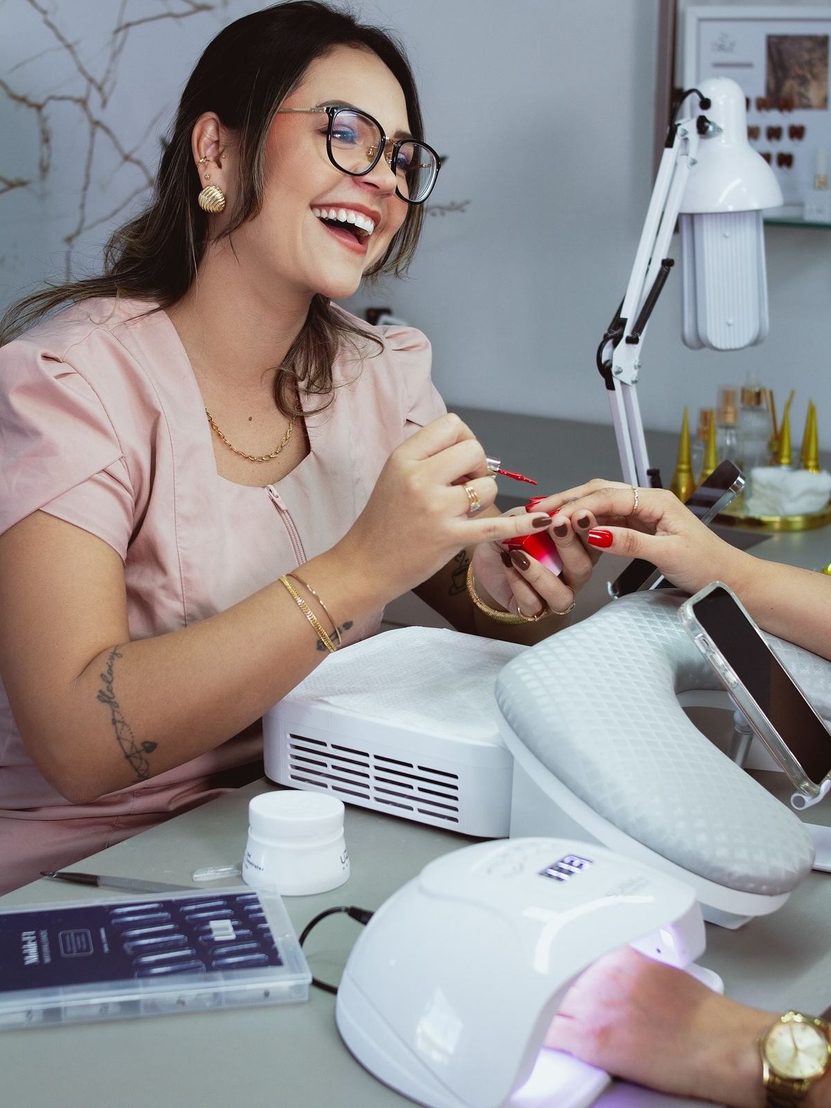Nail technician uploading nail design photos on a laptop and smartphone in a modern studio, demonstrating building an online presence for nail techs.