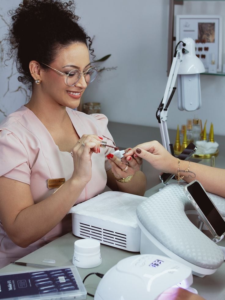 Nail technician practicing nail designs on tips in a clean studio, demonstrating ways to improve nail tech skills quickly