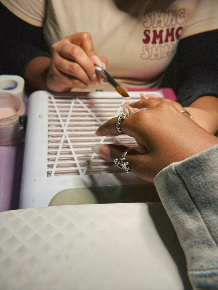 Nail technician improving services by carefully working on a client’s nails with attention to detail in a bright studio.