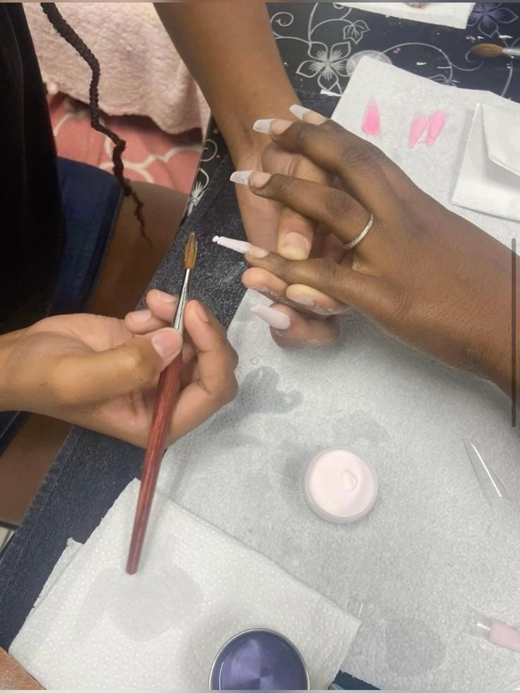 Nail technician presenting a pricing menu to a client, demonstrating professional pricing strategies for nail services.