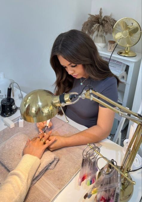 Nail technician giving a client a referral card, illustrating a system to grow nail business through referrals.