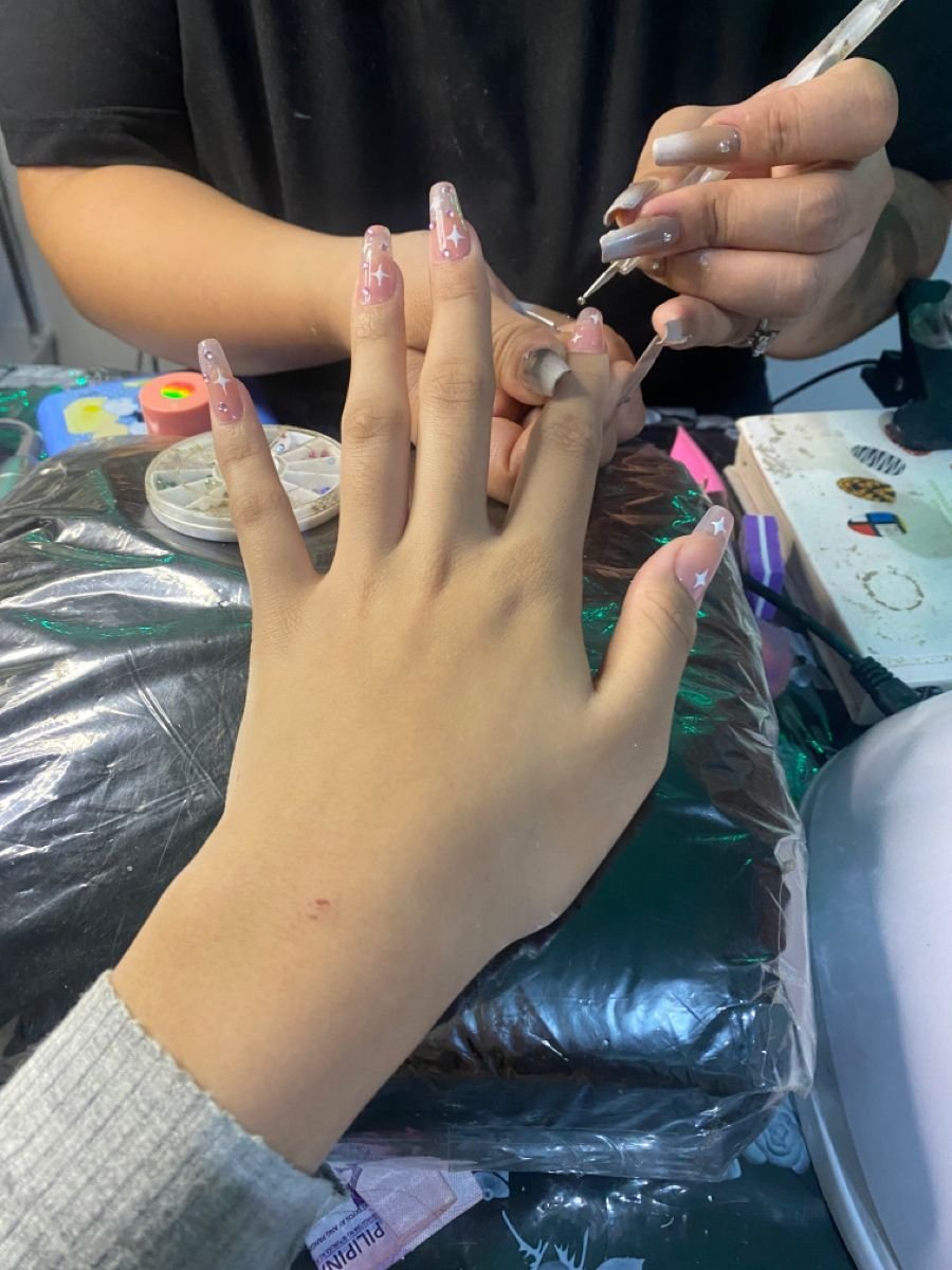 Nail technician giving a loyalty card to a client, demonstrating strategies to retain clients and grow a nail business.
