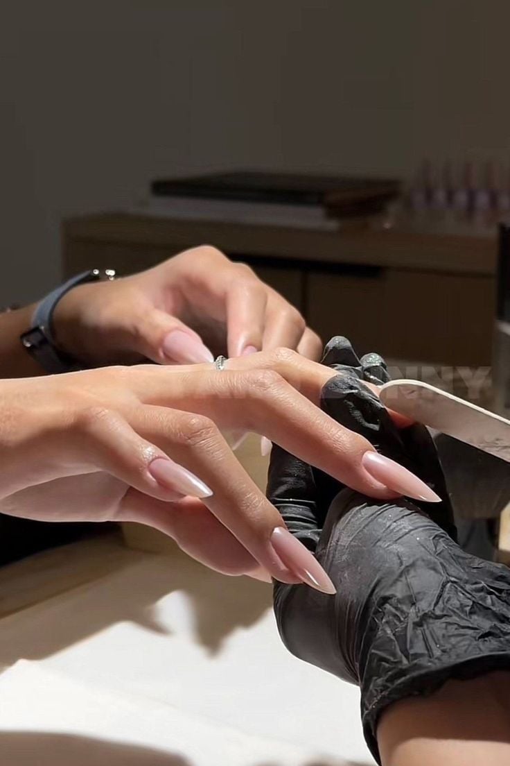 Nail technician giving a referral card to a client to encourage referrals and grow a nail business.