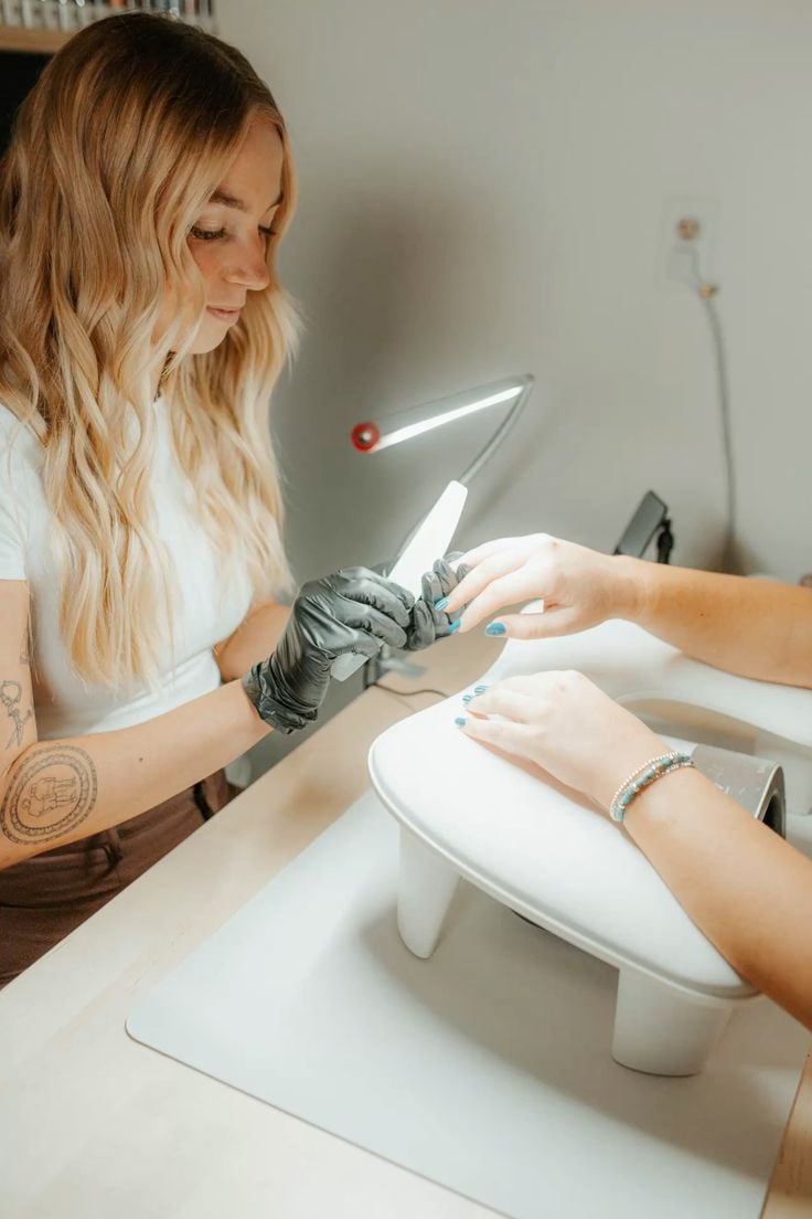 Nail technician learning new nail trends through an online tutorial at a modern salon.