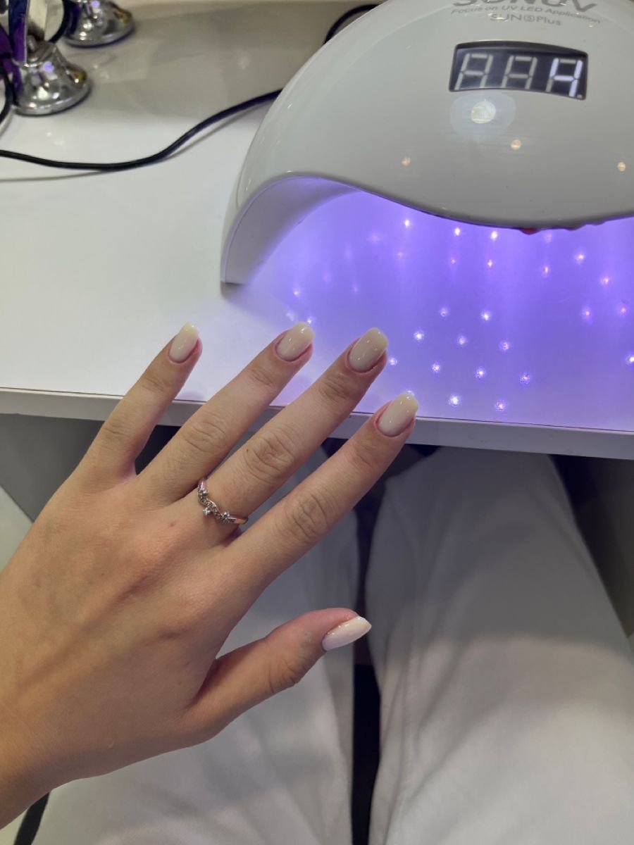 Nail technician professionally handling a client concern in a bright, welcoming nail salon.