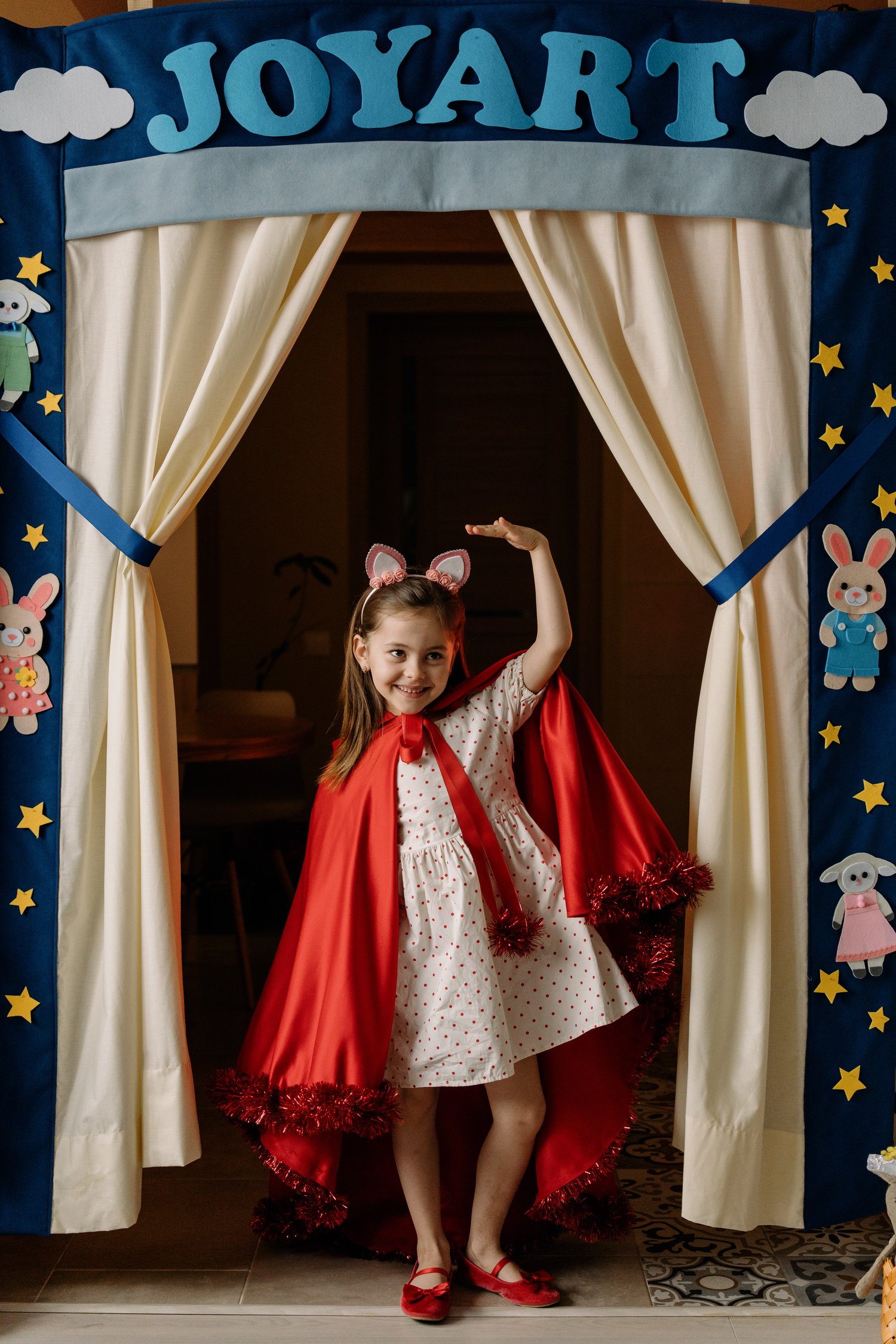 Child performing in JoyArt Doorway Theatre with cream curtains and star decorations – handmade puppet theatre PDF sewing pattern by MUNa Patterns