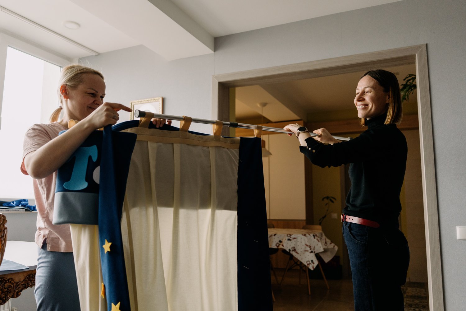 Two women assembling the JoyArt Doorway Theatre – handmade fabric puppet theatre sewing pattern for beginners