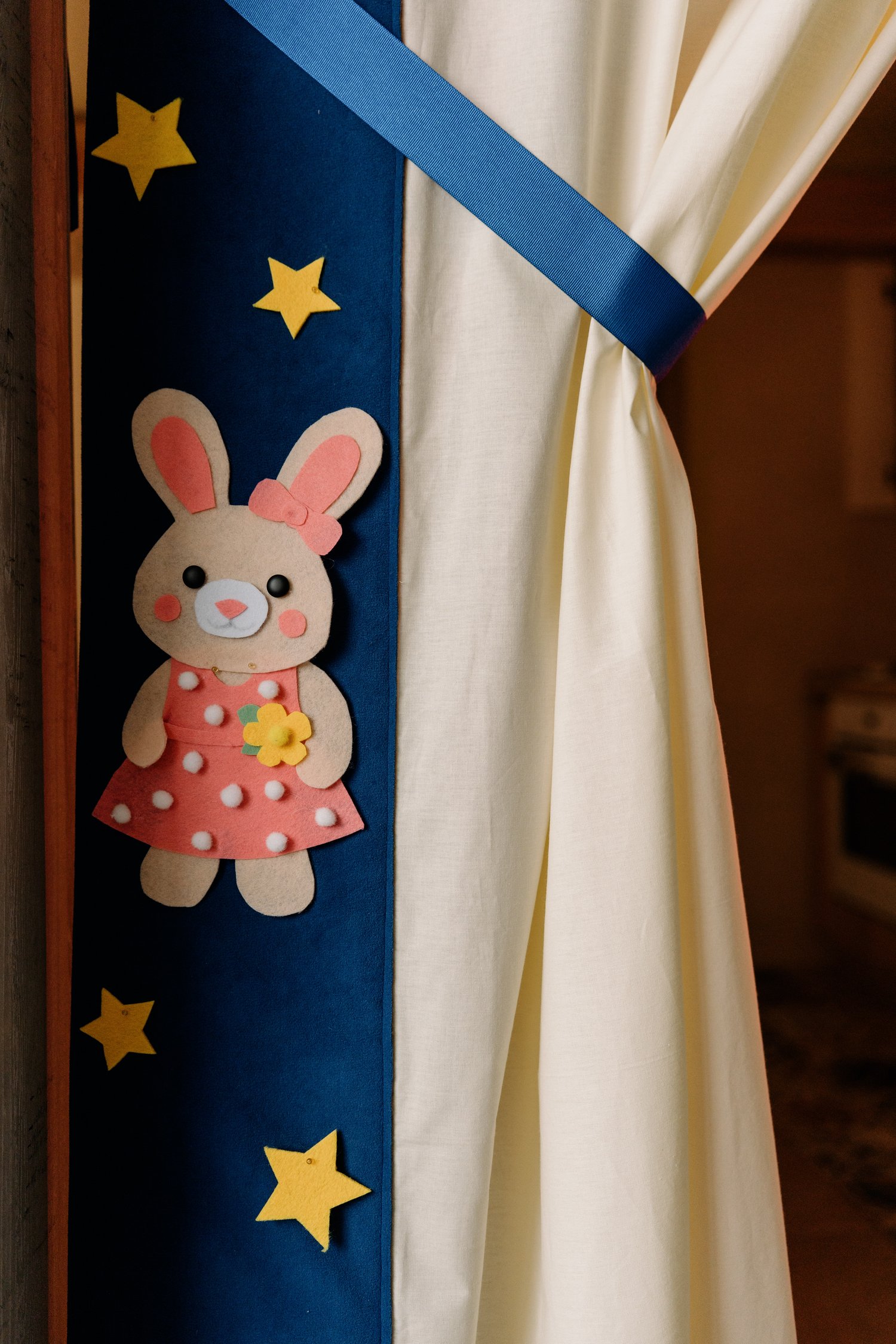 Handmade felt rabbit puppet hanging on JoyArt Doorway Theatre curtain – Easter felt character sewing pattern by MUNa Patterns