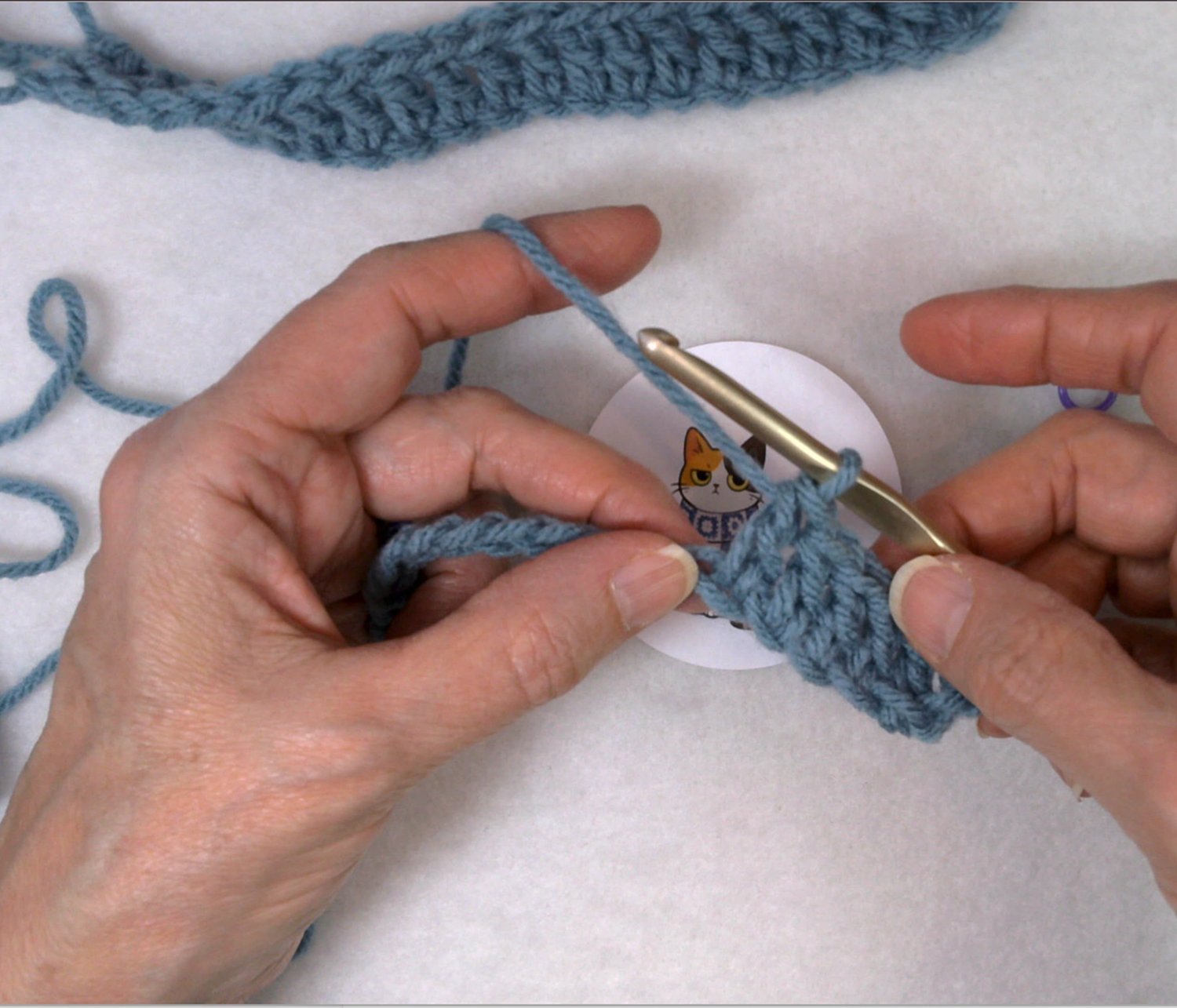 How to crochet into a chain for beginners, showing hands working stitches with yarn and crochet hook