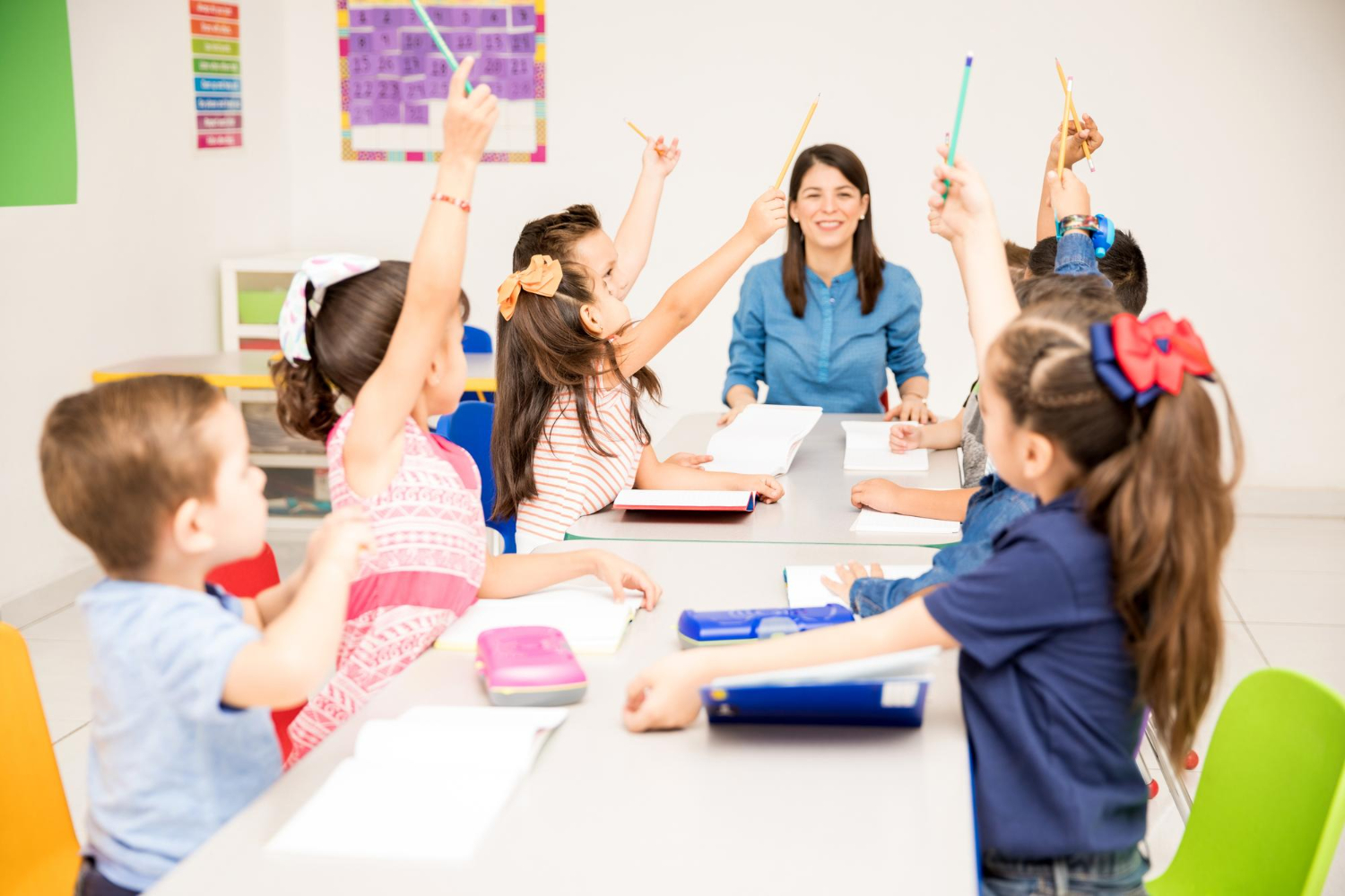 group of preschool students raising their hands during class and trying to participate