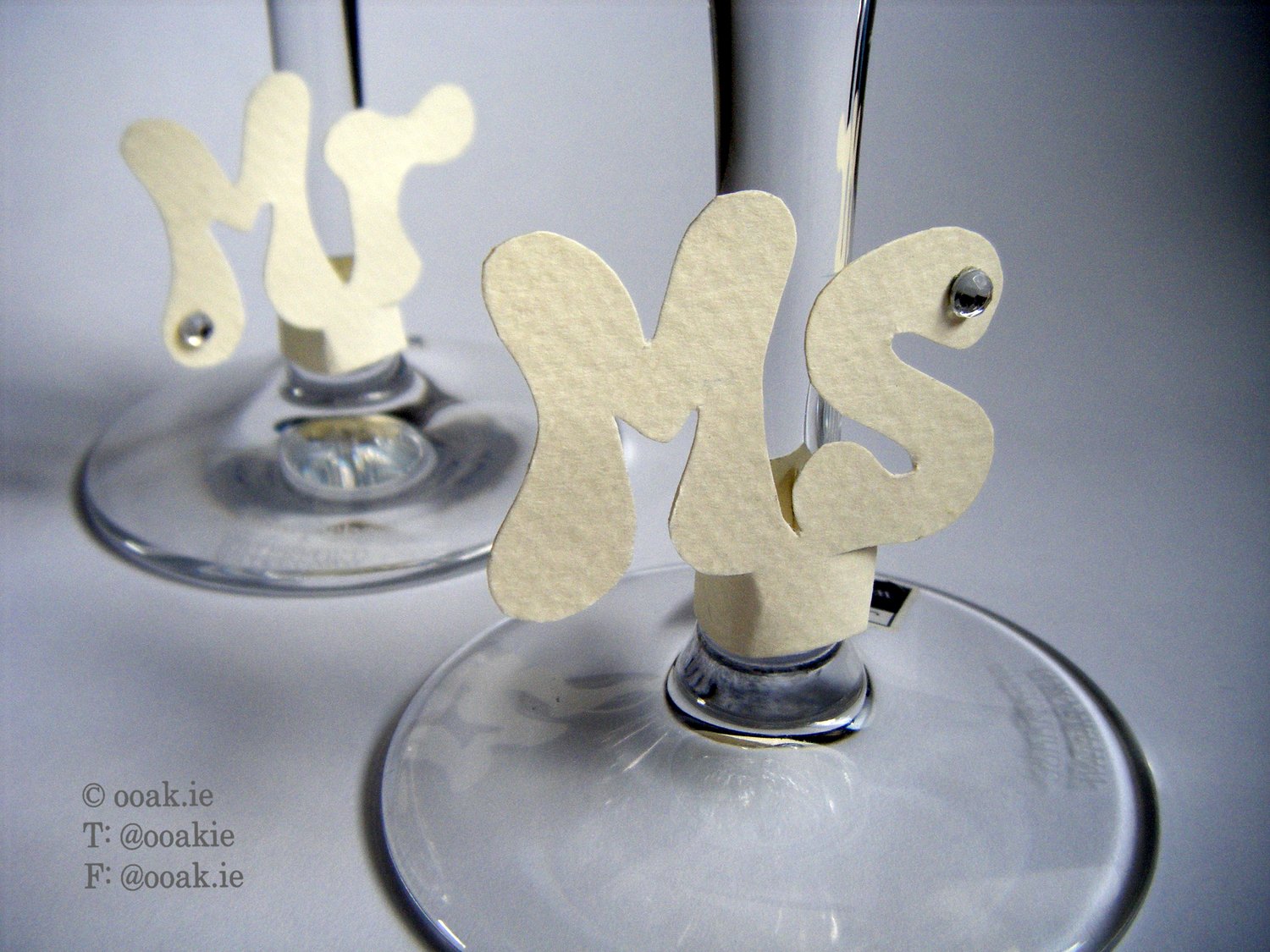 Mr and Ms wine glass tags made from cream card embellished with crystals in use on the stems of wine glasses