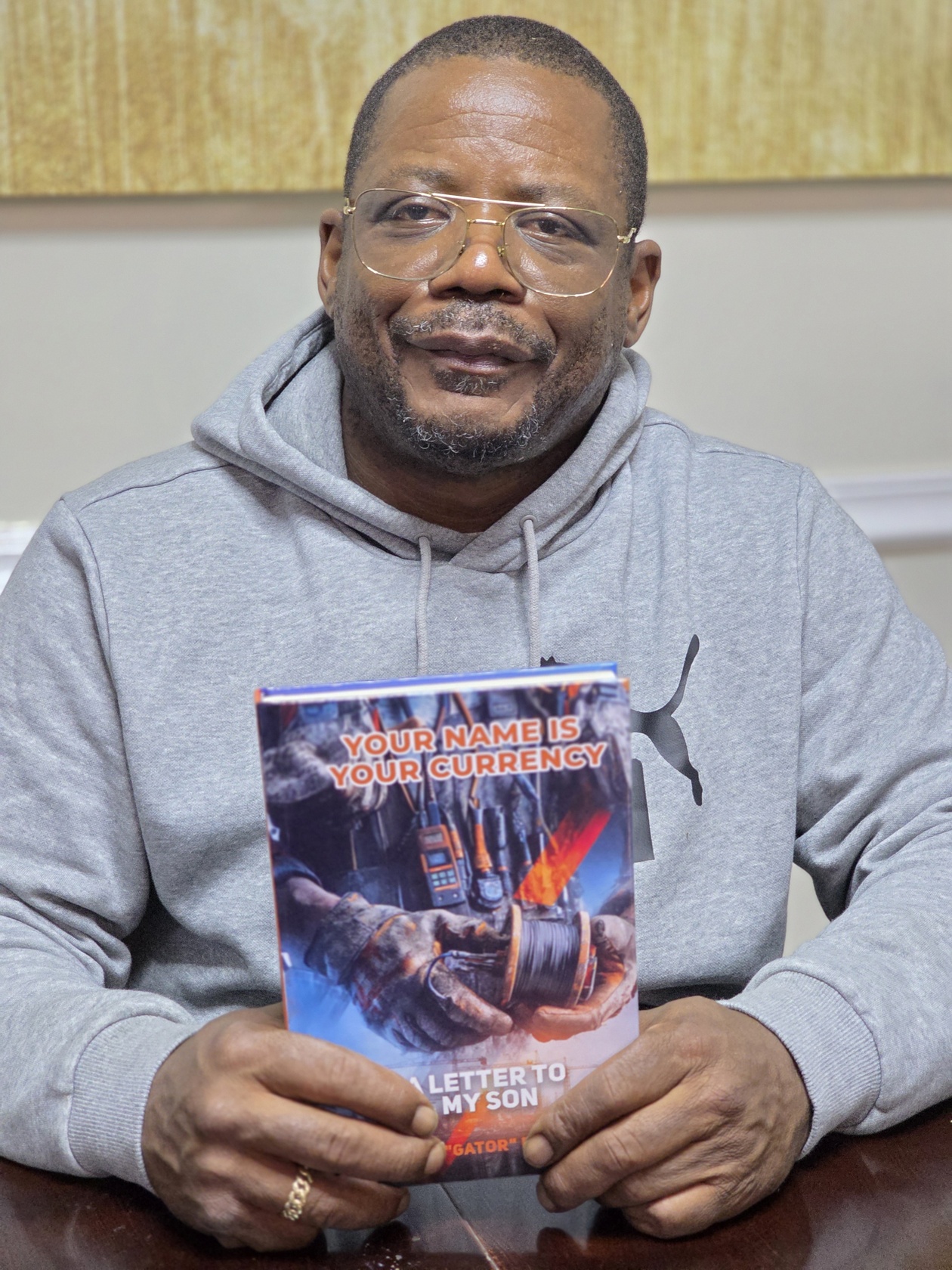 Andre Gator Daniels holding Your Name Is Your Currency book