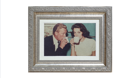 Framed vintage illustration of a couple sharing coffee, mid-century style artwork in ornate silver frame