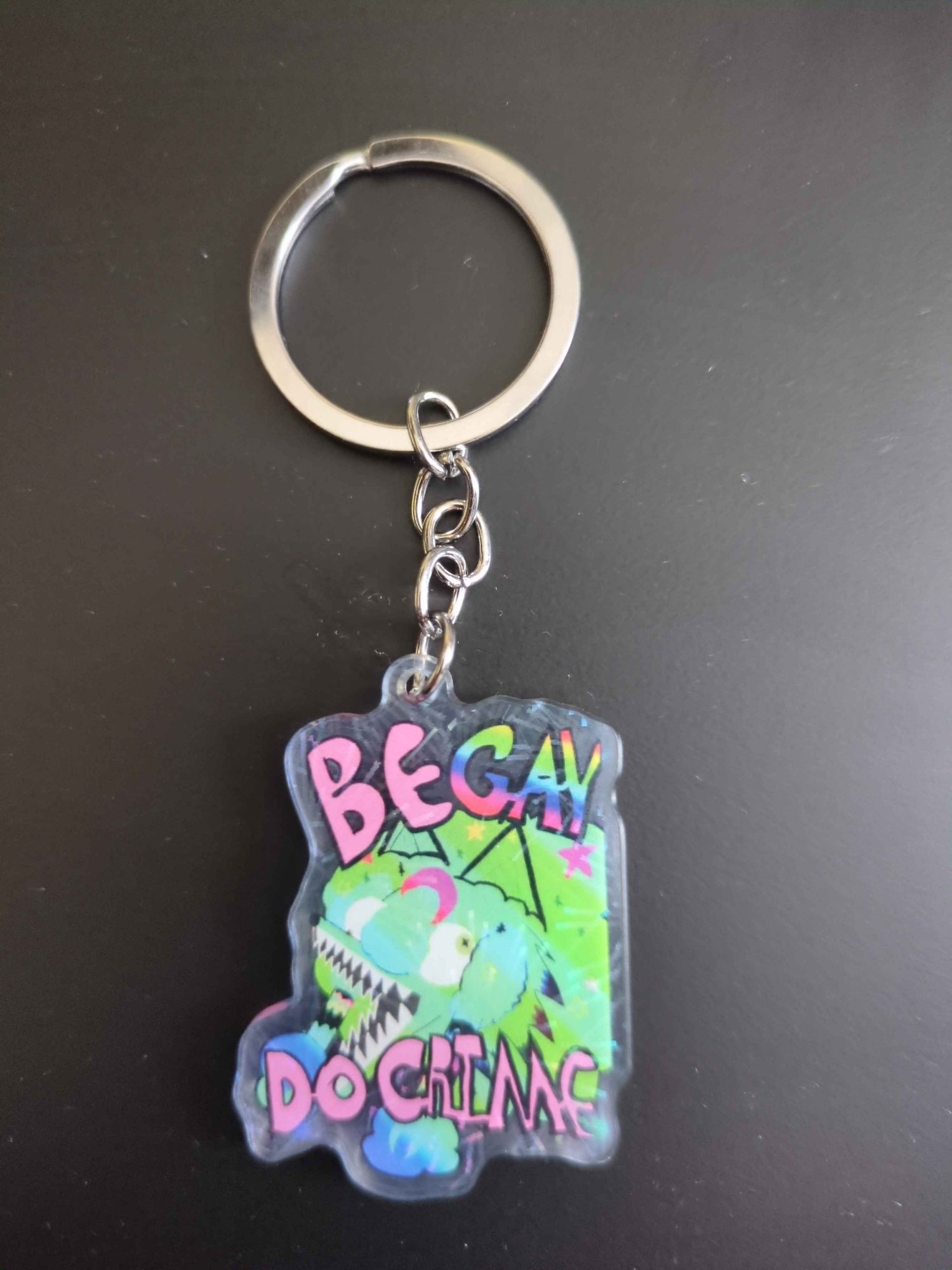 Green Sparkle COyote girl head in green sparkles covered in stars and moons blue green gradient with pink text that reads "Be Gay Do Grime" Gay text is rainbor. Wide mouth, braids and eyes looking the wrong directions. front