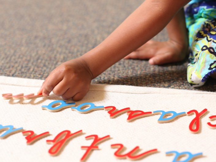 A kid using mobile montessori letters to learn how to write