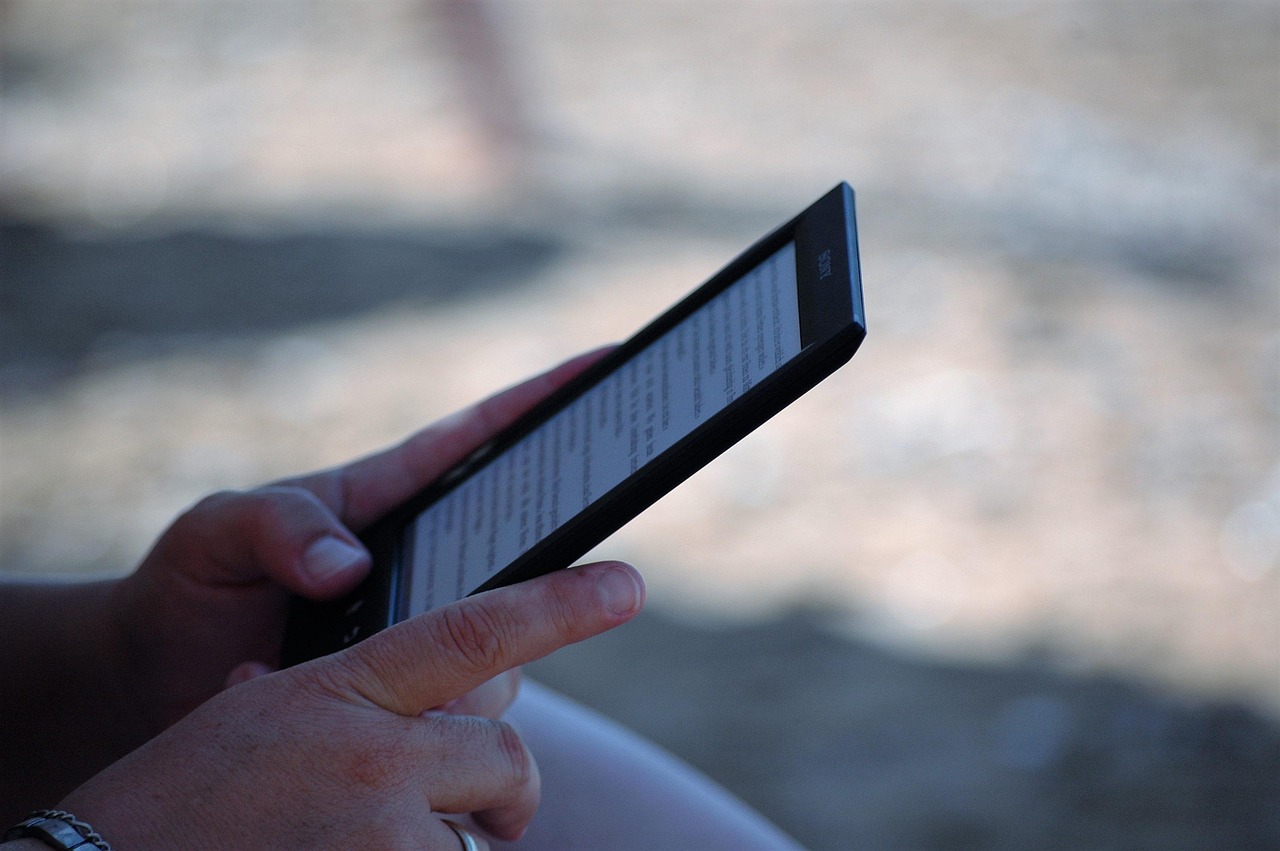 a pair of hands holding a Kindle eBook reader