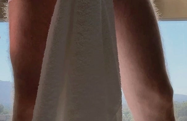 Editorial self-portrait of a man standing in front of a window holding a white towel, photographed in warm natural morning light with cinematic shadows and a minimalist interior atmosphere