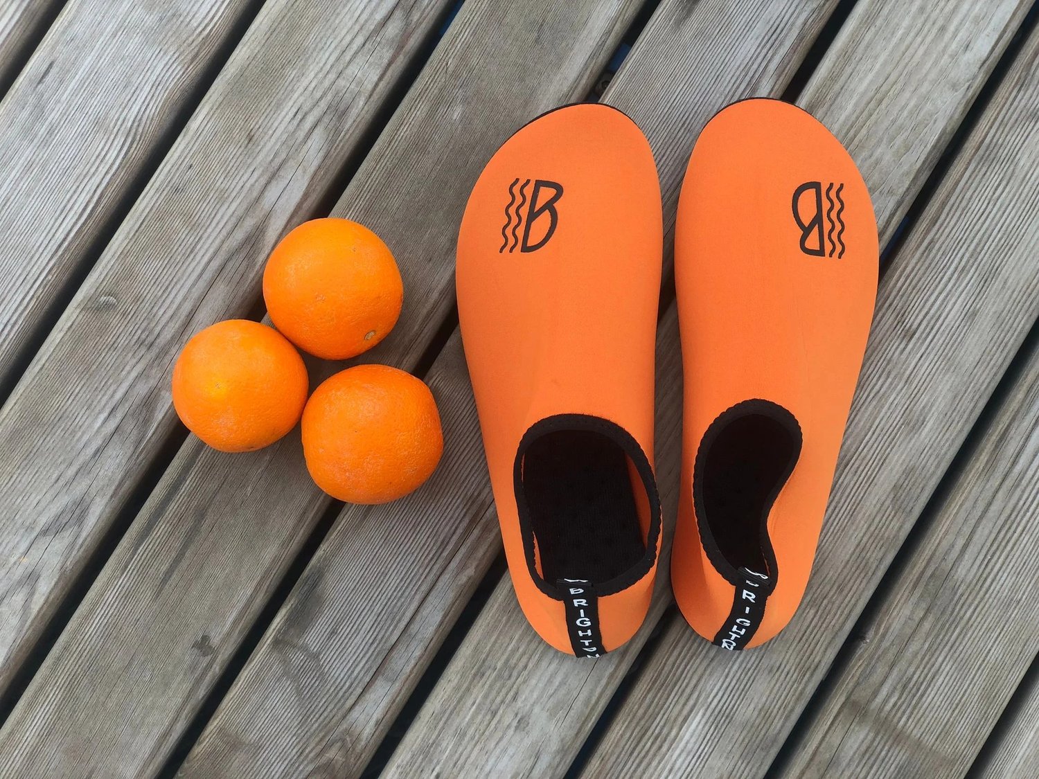 Orange water shoes alongside some oranges
