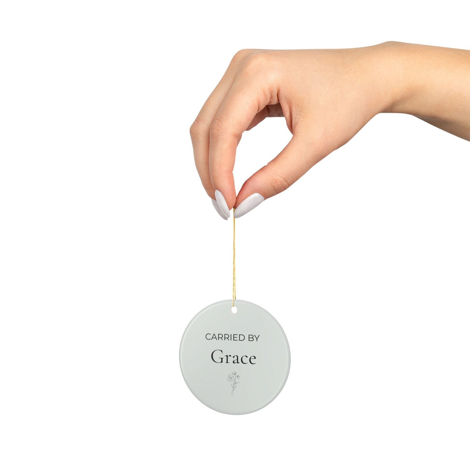 Carried By Grace sage ceramic ornament held by hand for size reference.