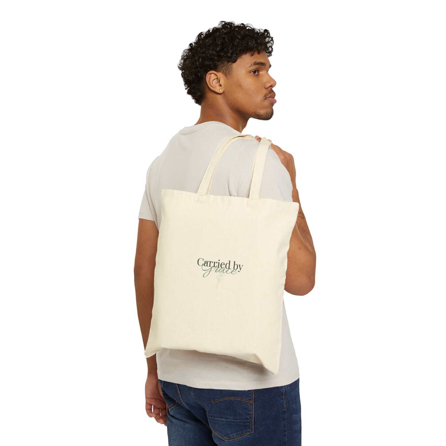 Model holding the Carried by Grace cotton tote bag, showing the front text design clearly