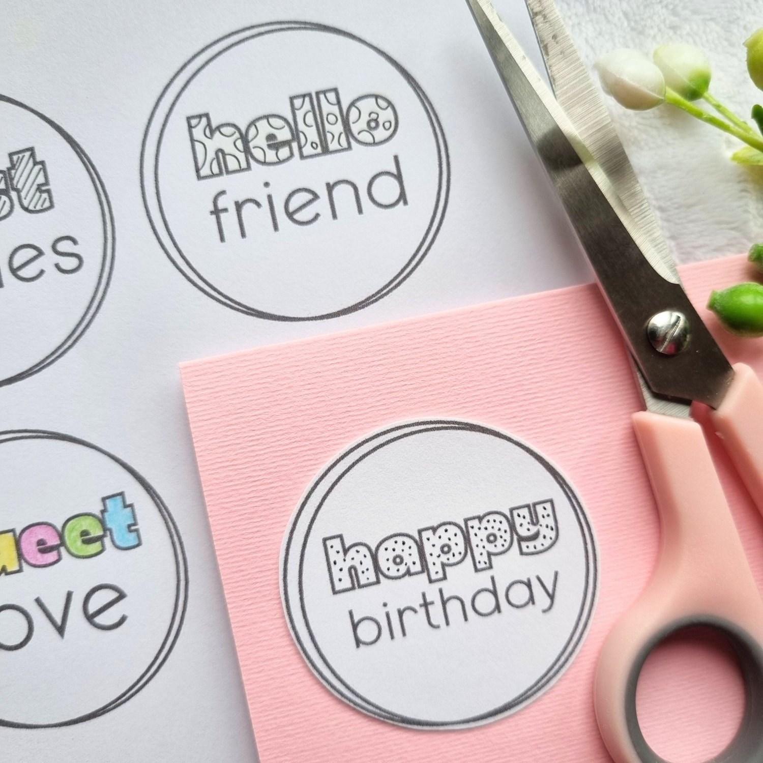 Circular printable card making sentiments next to a pink card base and pink scissors.