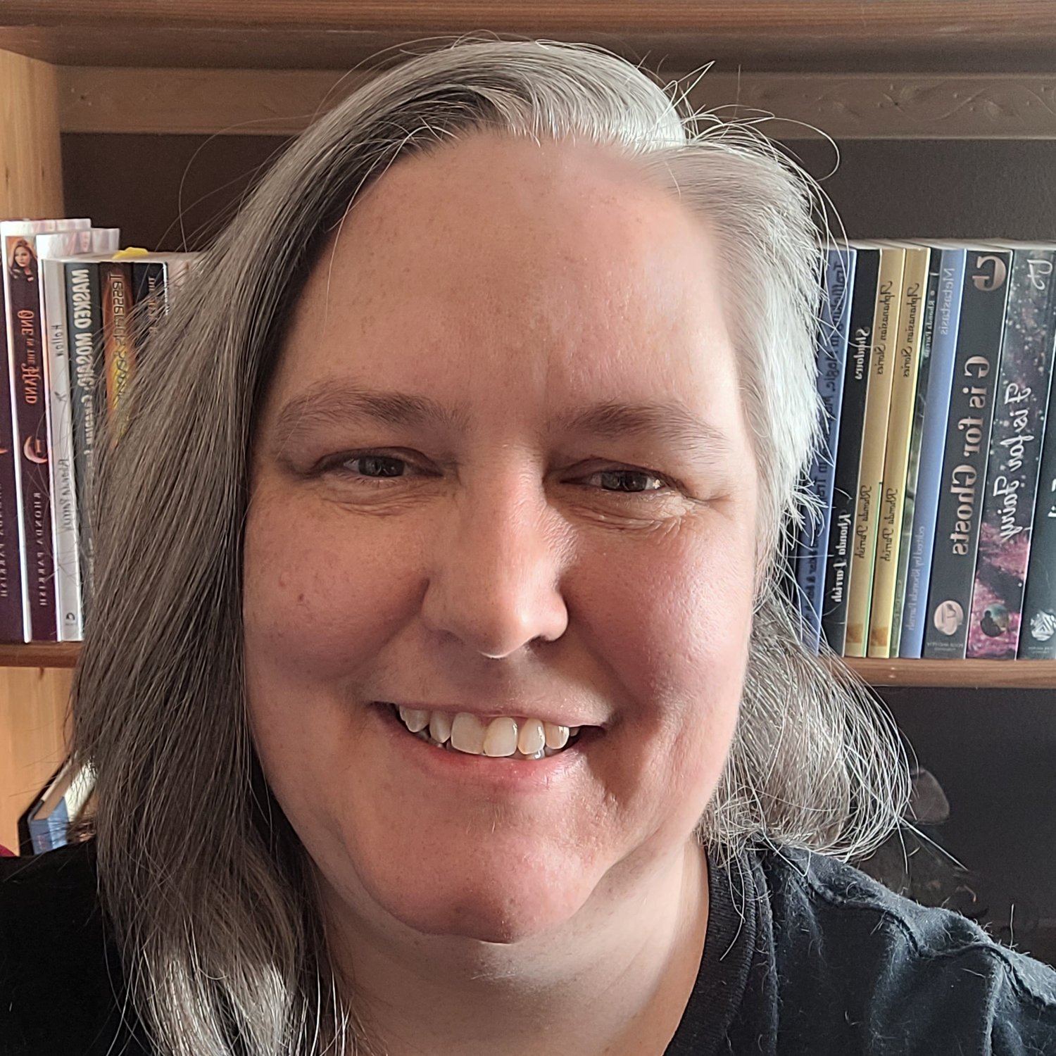 Rhonda Parrish smiling in front of a bookshelf showing some of her titles