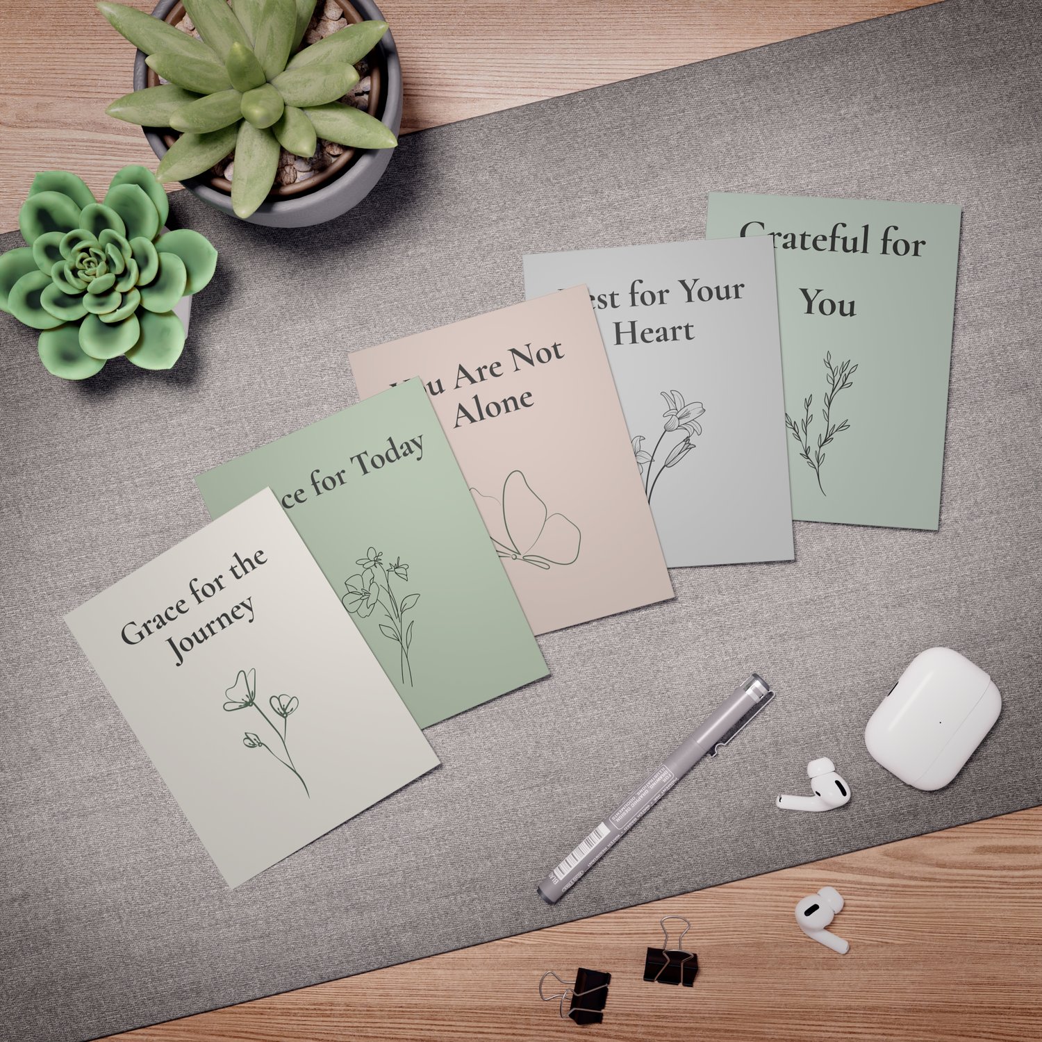Five caregiver encouragement cards arranged flat on a soft background with a succulent, pen, and earbuds, featuring simple botanical and butterfly illustrations.