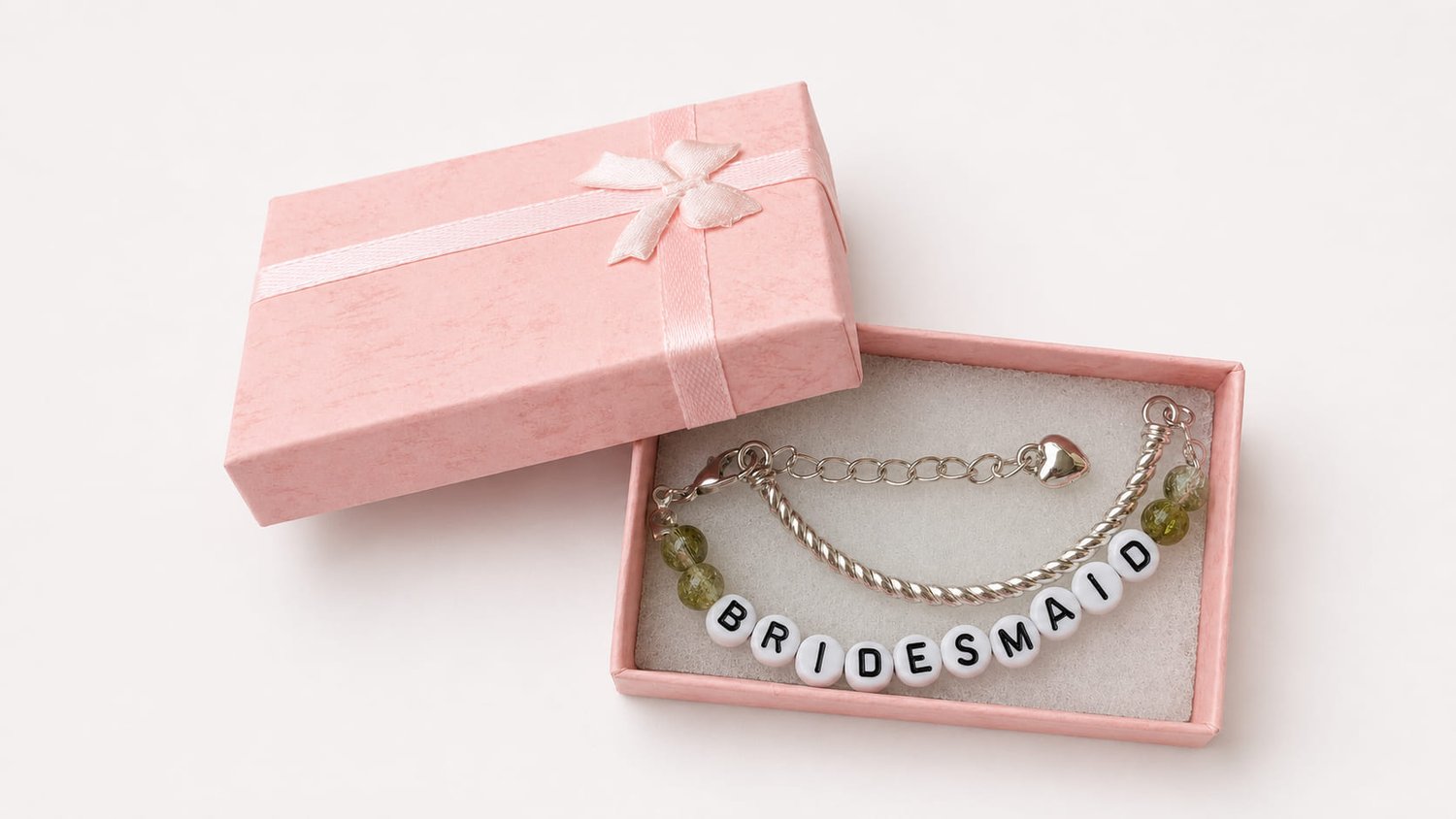 Handmade bridesmaid charm bracelet featuring a silver twisted bangle, olive green crackle glass beads, white and black BRIDESMAID letter beads, and a dangling silver heart charm. in pink luxury box