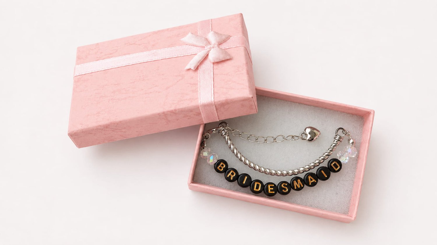 Handmade bridesmaid wire bracelet featuring faceted clear crystal beads, black and gold BRIDESMAID letter beads, and a dangling silver heart clasp extender. in pink luxury box