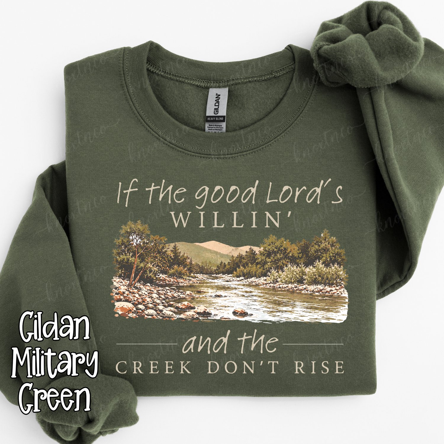 If the Good Lord’s willin’ and the creek don’t rise Christian Southern saying design with a vintage mountain creek scene, shown on a Gildan military green sweatshirt.