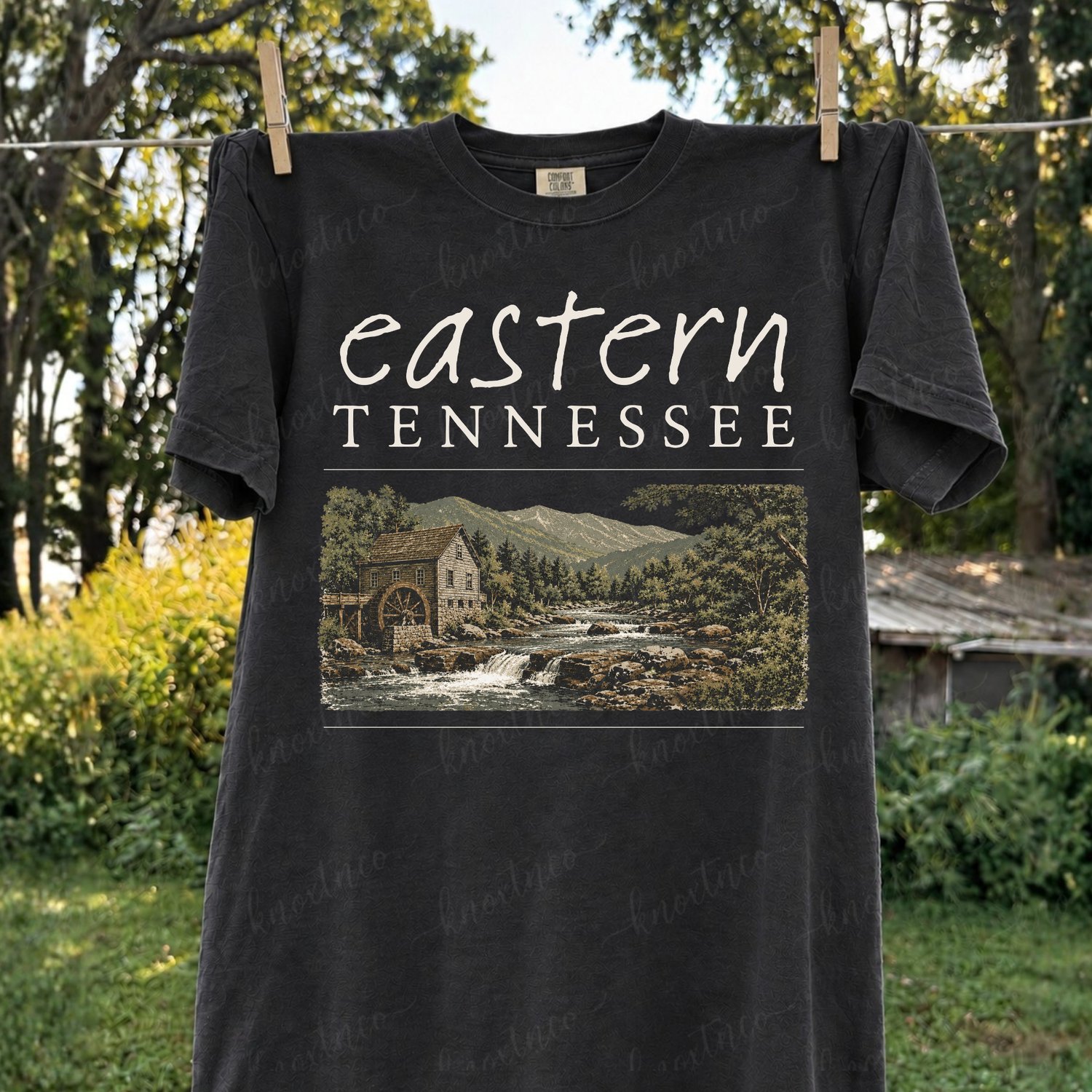 Eastern Tennessee Comfort Colors t-shirt featuring a vintage mountain landscape with a rustic mill, river, trees, and Appalachian scenery, available as a t-shirt or Gildan sweatshirt.