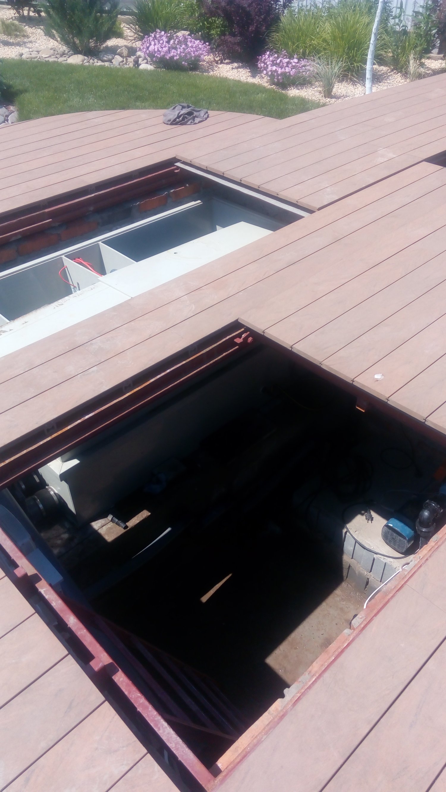 Technical equipment room hidden beneath the deck of a natural swimming pond, housing filtration, circulation and aeration systems.