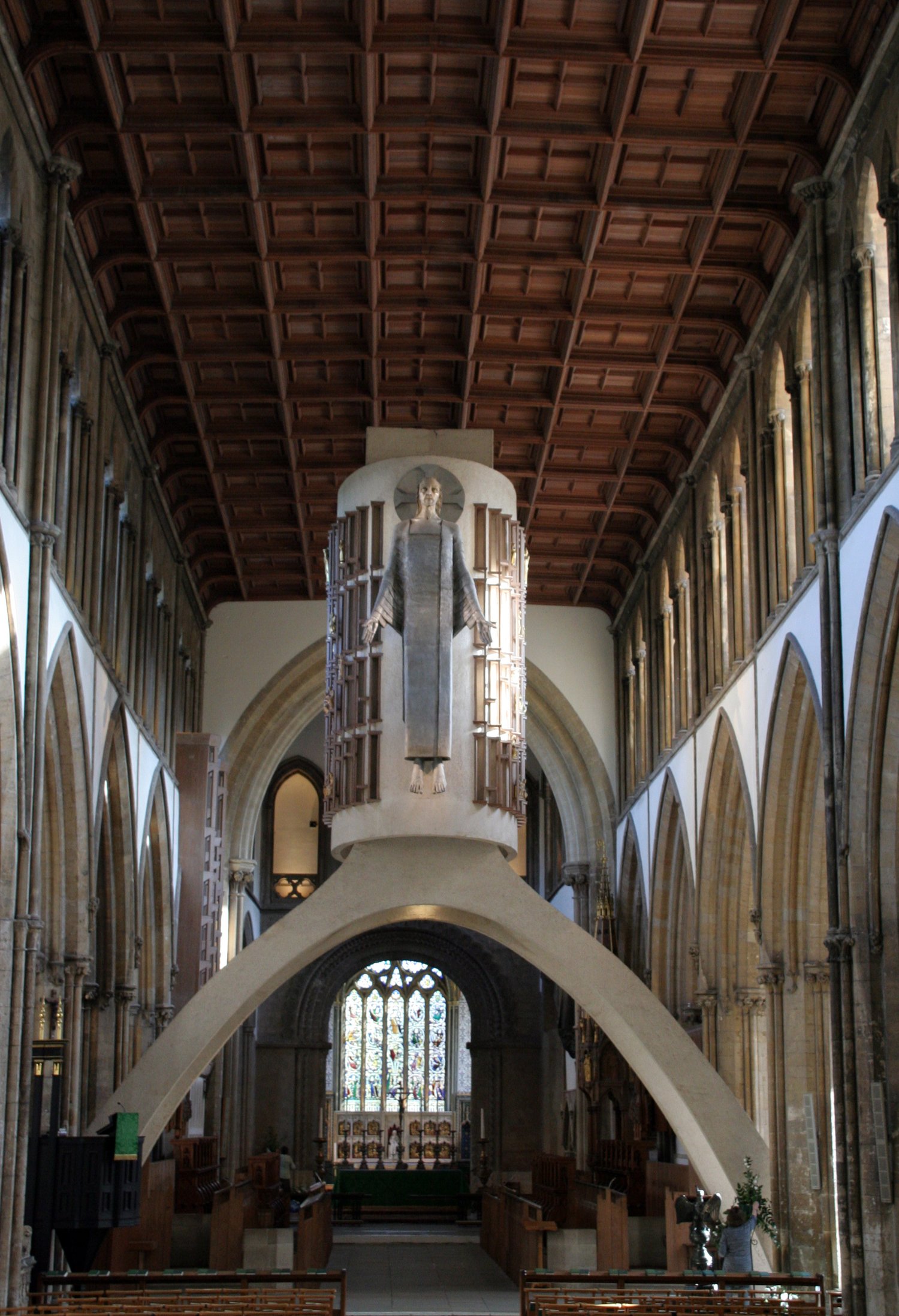In Llandaff Cathedral, A large cylinder is on top of an arch just in front of the choir stalls. On the cylinder is a large modernist statue of Christ in Majesty. The east window can be seen below the arch.