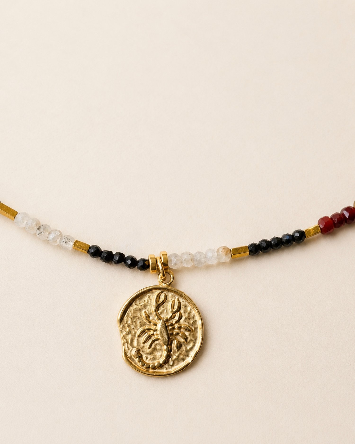 Dettaglio del pendente dorato Scorpione e delle pietre naturali da 2 mm.