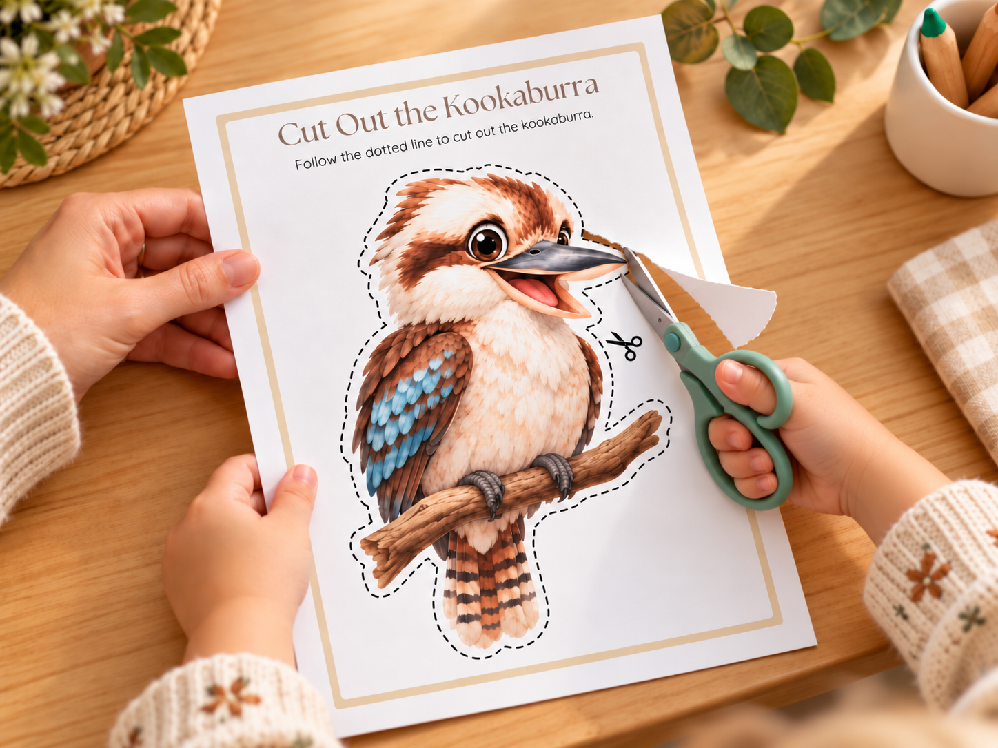 Preschool child practising scissor skills by cutting out a kookaburra worksheet with child-safe scissors