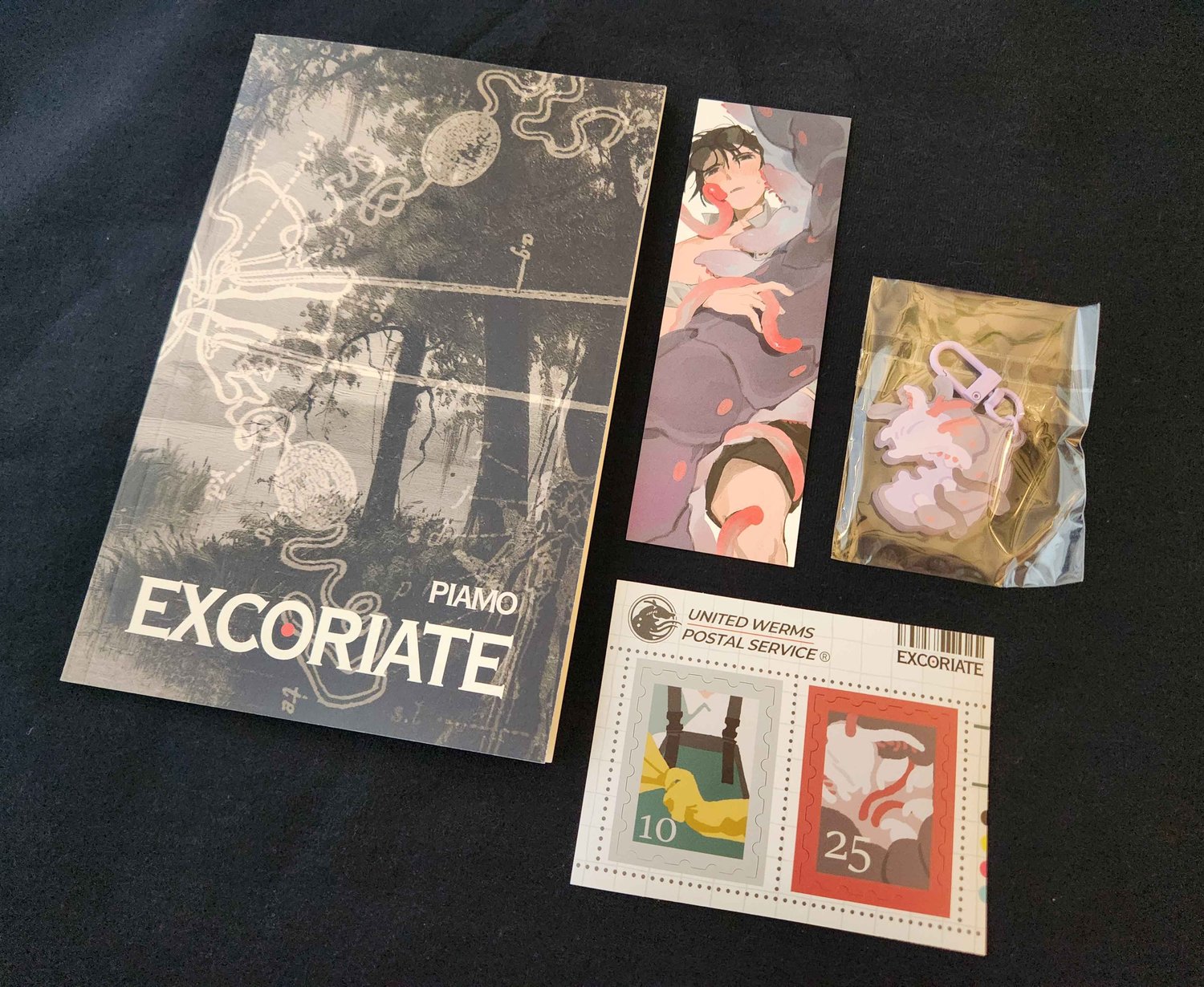 a photograph of a book, a bookmark, stickers, and an acrylic charm
