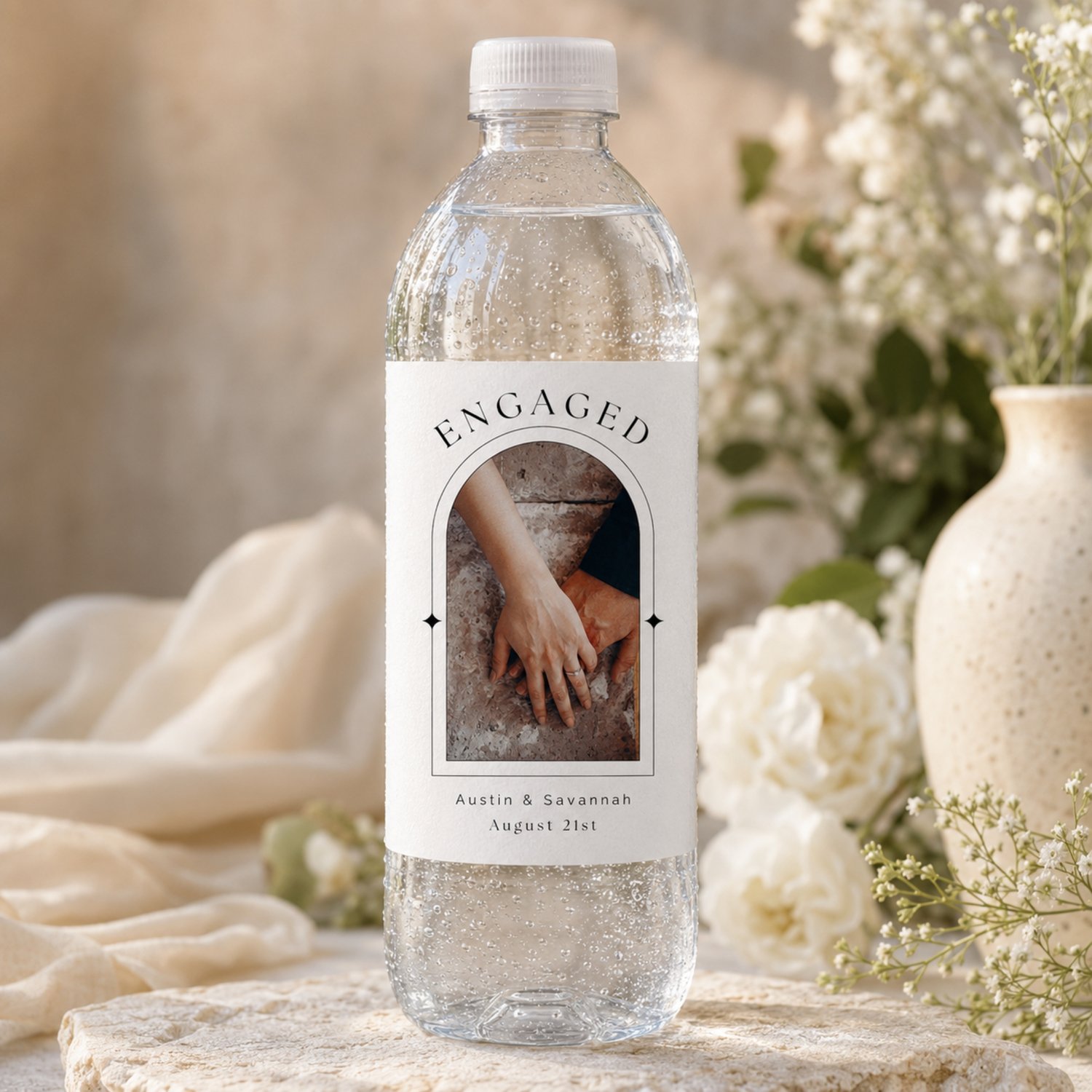 Editable 4 by 6-inch engagement bottle label template featuring a couple’s photo, names and date in a modern black-and-white arched design, with two labels arranged on a letter-size printable sheet.