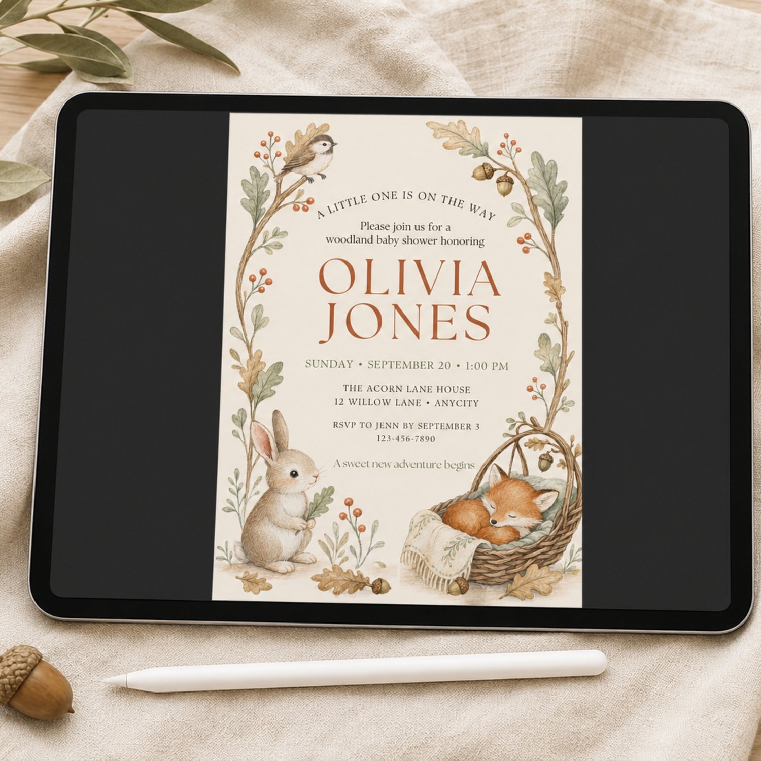 Editable 5 by 7 woodland baby shower invitation featuring a bunny, sleeping fox, bird, acorns, autumn leaves and neutral forest botanicals.