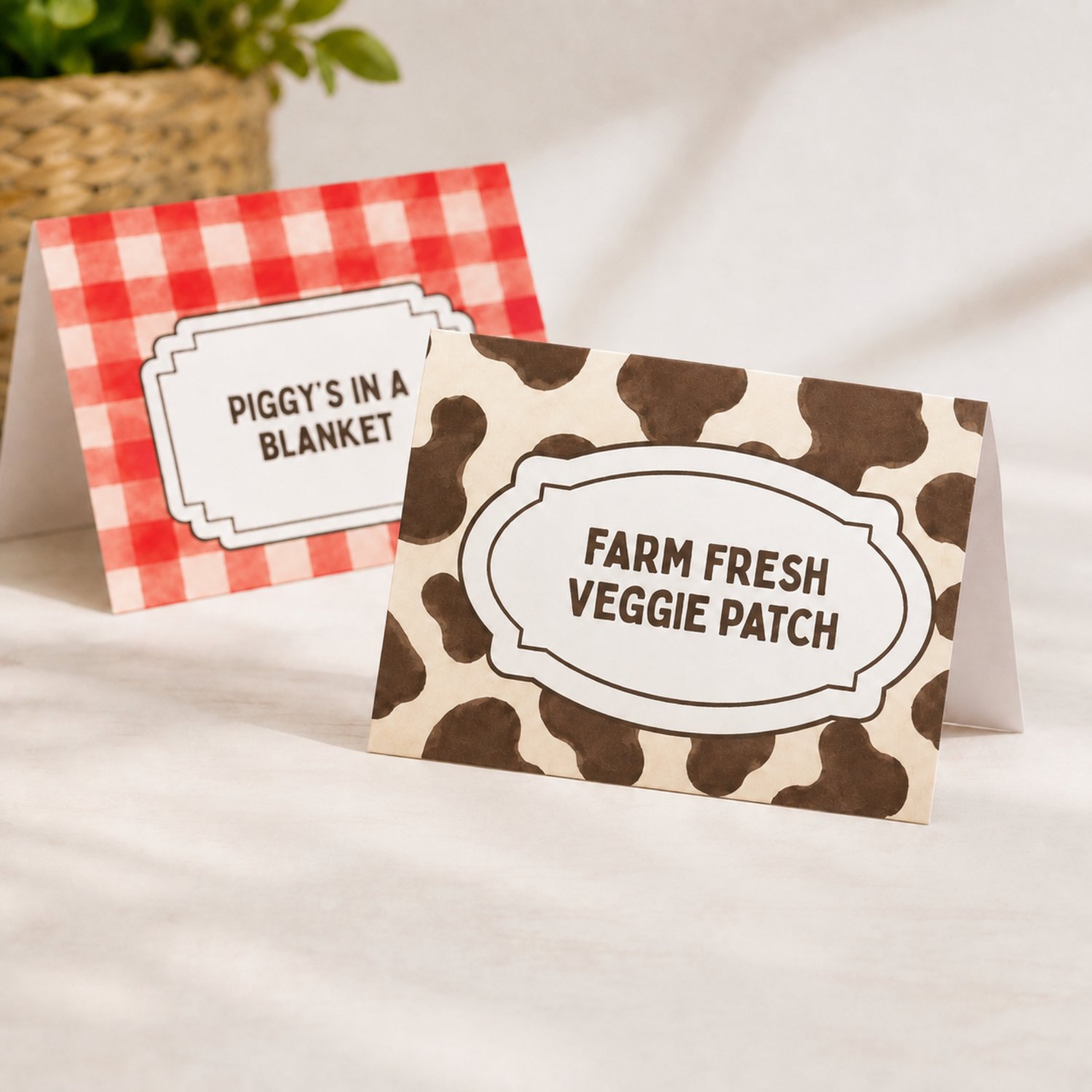 Four editable barnyard birthday folded food-label cards featuring red gingham and brown cow-print patterns with sample farm-themed food names, arranged on a printable letter-size sheet.