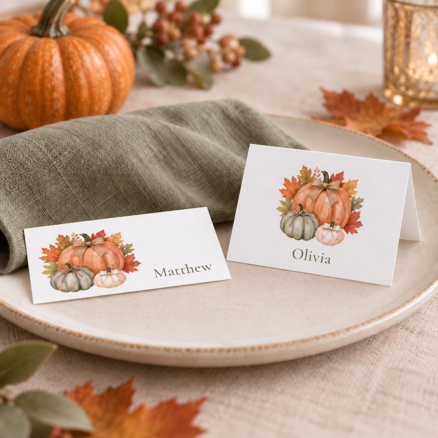 Editable fall place card templates featuring watercolor orange, sage and cream pumpkins with rustic bows and autumn leaves. Includes printable flat and folded tent name cards for Thanksgiving dinners, Friendsgiving and fall celebrations.