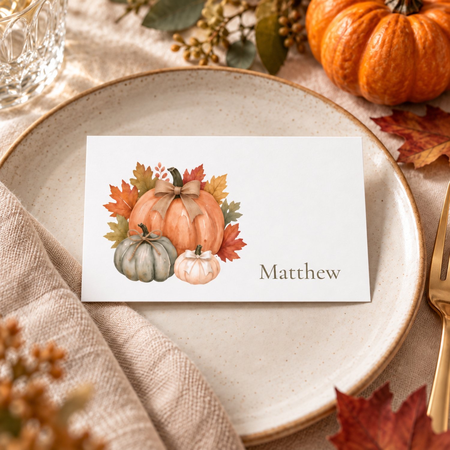Editable fall place card templates featuring watercolor orange, sage and cream pumpkins with rustic bows and autumn leaves. Includes printable flat and folded tent name cards for Thanksgiving dinners, Friendsgiving and fall celebrations.