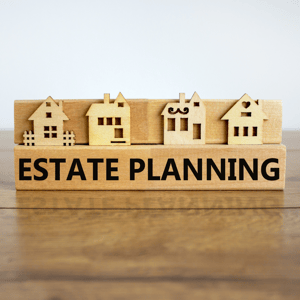 wooden sign with small house cutouts with words estate planning in black text