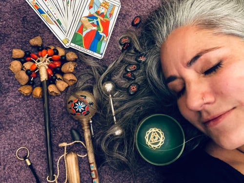 Image o a woman’s face next to tarot cards, runes and instruments