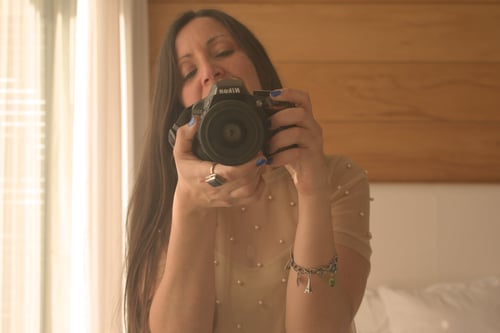 Giselle is holding her camera in front of a mirror.